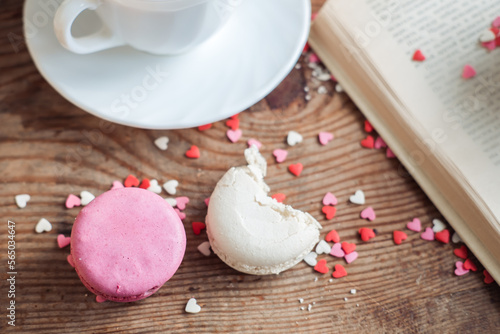 Lavender and almond macaroon with a bitten off piece on a wooden background, with small hearts. photo