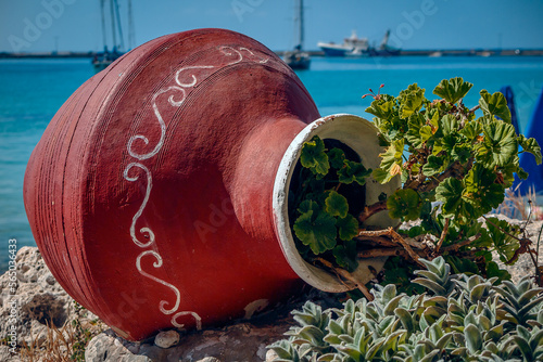 Photography Close Up of a red ornate ceramic pot filled with geraniums set again the harbour