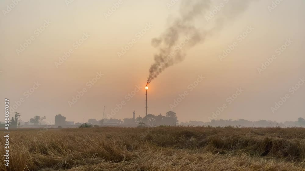 Static establisher view of industry area with Gas Plant tower releasing polluting fumes, orange hazy sunset sky Static establisher view of industry area with Gas Plant tower releasing polluting fumes, orange hazy sunset sky