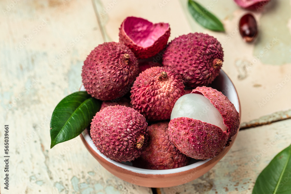 Fresh lychee and peeled showing the red skin with cut in half and leaves, Food background. Close up Fresh lychee and peeled showing the red skin with cut in half and leaves, Food background. Close up
