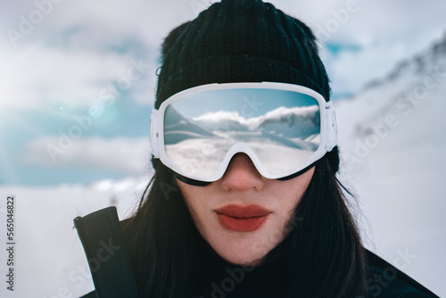Close up of the ski goggles of a woman with the reflection of snowed mountains