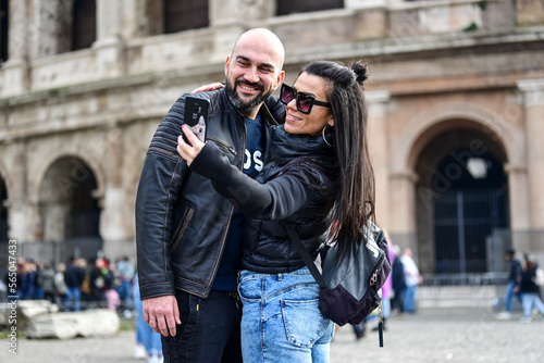 Happy Tourists couple traveling at Rome, Italy, poses in front of Altar of the Fatherland (Altare della Patria) and Piazza Venezia at, Rome, Italy