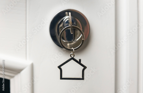Up close A key with a keychain in the form of a house in a door lock. The concept of buying a new home.