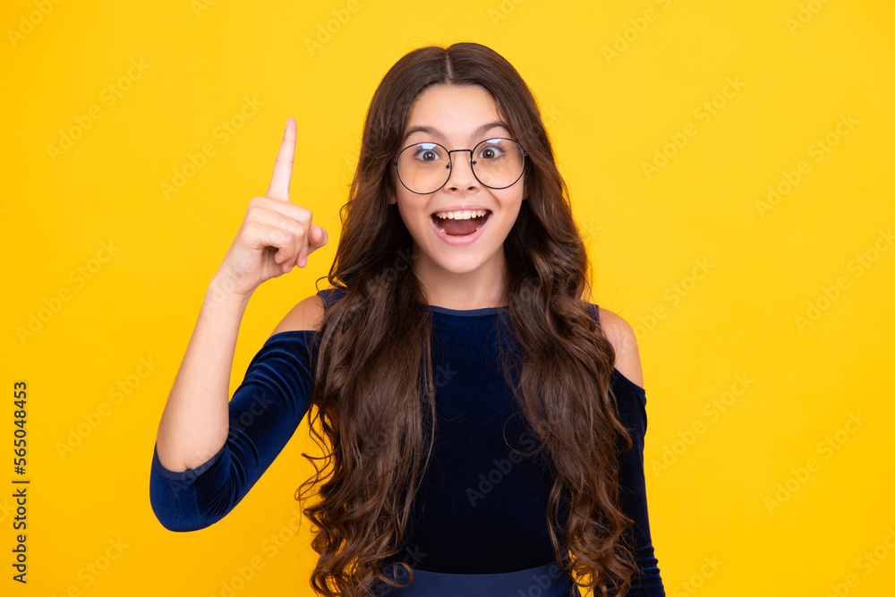 Excited teenager girl. Close up funny face of young teenager pointing up with finger, isolated on yellow background. Girl has great new idea. Successful child. Excited teenager girl. Close up funny face of young teenager pointing up with finger, isolated on yellow background. Girl has great new idea. Successful child.