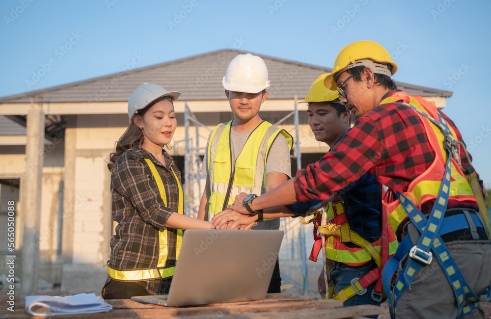 Engineer teamwork in a construction building.Engineers construction and two safety suit workers at a building site with a home construction Engineer teamwork in a construction building.Engineers construction and two safety suit workers at a building site with a home construction