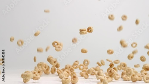 Whole grain cheerio cereal bouncing into pile on white table top in slow motion photo