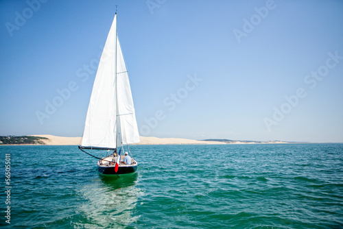 Sailboat sailing with Dune of Pilat in background, Banc d'Arguin, Arcachon Bay, France photo