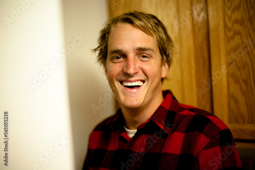 A young man wearing a red flannel jacket smiling at a camera in Camarillo, California. photo