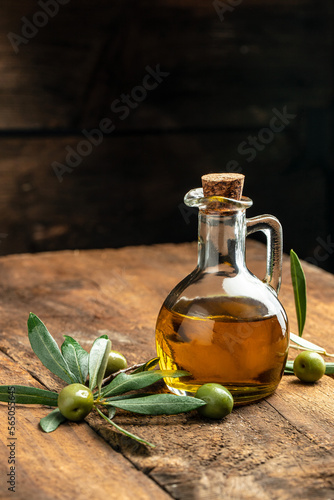 Olive oil in bottles with black and green olives and leaves. extra virgin olive oil jars on a wooden background. vertical image. top view. place for text