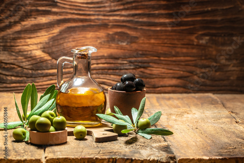 Glass container with olive oil branches and olives on a wooden background. Long banner format