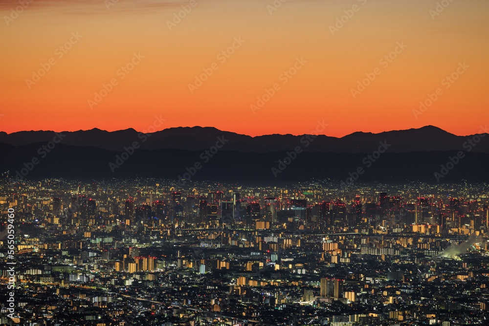 Lights from sprawling city with orange dawn glow over distant mountains