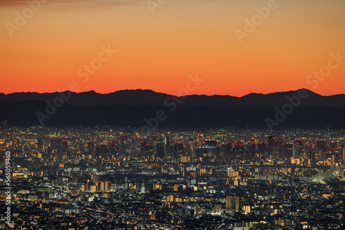 Lights from sprawling city with orange dawn glow over distant mountains