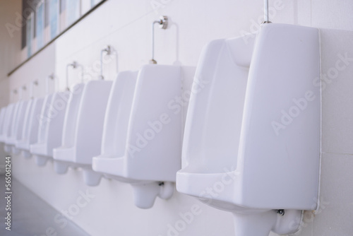 Row of clean and  hygiene white urinals in men's public outdoor restroom, design of white ceramic urinals for men in toilet room © Weerawich