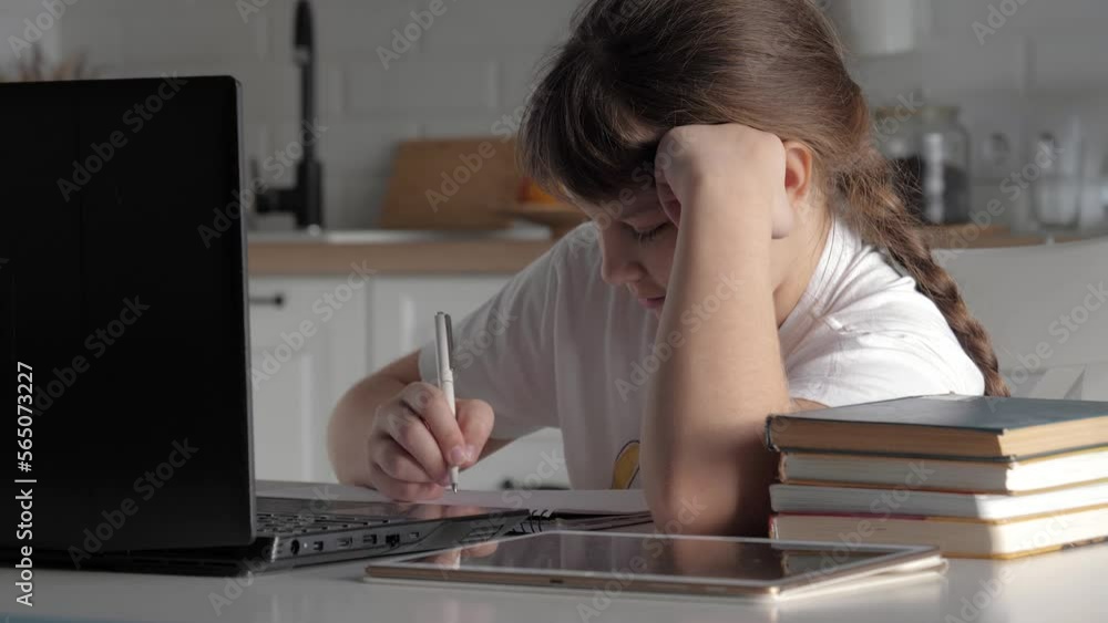 Sad girl sitting at table home. Schoolgirl too lazy to do homework. Writes pen in workbook. Teenager thinking about solving school lesson. Bad mood and dream about vacations. Transitional age children Sad girl sitting at table home. Schoolgirl too lazy to do homework. Writes pen in workbook. Teenager thinking about solving school lesson. Bad mood and dream about vacations. Transitional age children
