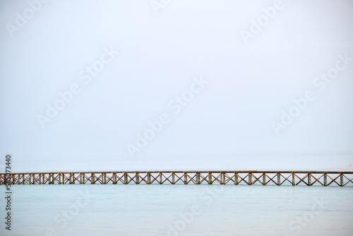 Long horizontal pier bridge on blue sky and water copyspace background