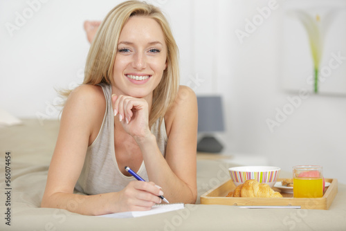 Schilderij op canvas woman writing diary while having breakfast in bed