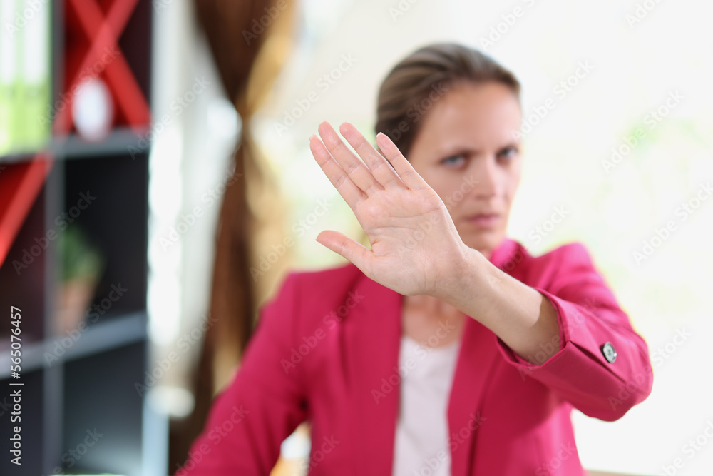 Serious female manager showing disagreement gesture while sitting in office.