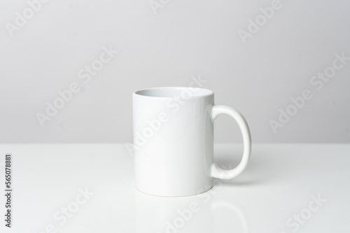 A white blank coffee mug on the top of a white table with a white background