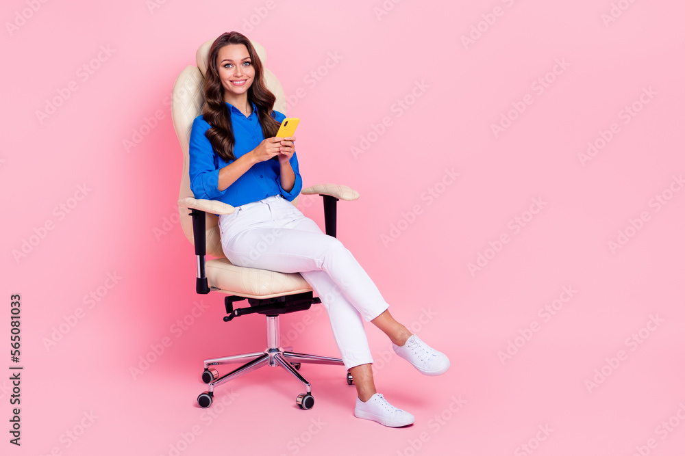 Full length cadre photo woman sitting comfortable chair use iphone online app for business tasks remote work isolated on pink color background Full length cadre photo woman sitting comfortable chair use iphone online app for business tasks remote work isolated on pink color background