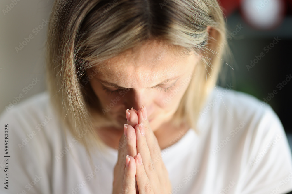 Woman with serious face holds her hands near her face as gesture of prayer. Woman with serious face holds her hands near her face as gesture of prayer.