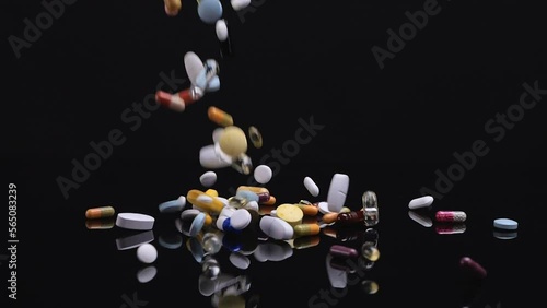 Different pills falling on black background. Drugs, pills, antibiotics, vitamins, healthcare, pharmaceutical industry, drug use, medicine concept. Slow motion