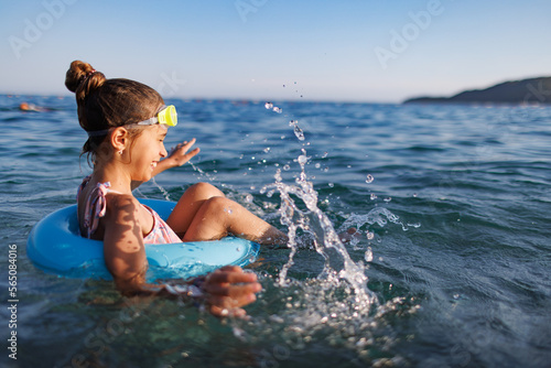 Canvas Print Cheerful girl sits in an inflatable circle and splashes with water in the sea