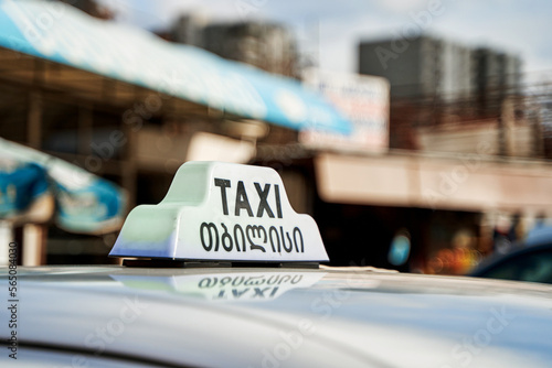 A checkerboard of a Georgian cab in the background of the city