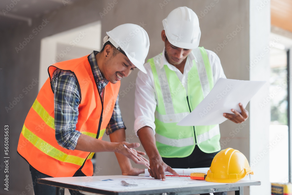 Two Asian male engineers are inspecting a job site and looking at drawings, consulting and debugging works to achieve quality work. Two Asian male engineers are inspecting a job site and looking at drawings, consulting and debugging works to achieve quality work.
