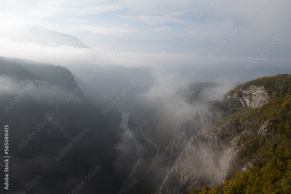 Mountain viewpoint over river canyon obscured in fog and clouds during autumn morning, misty mountain landscape Mountain viewpoint over river canyon obscured in fog and clouds during autumn morning, misty mountain landscape