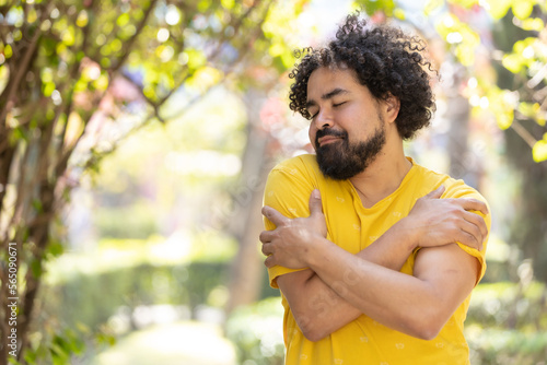 young Mexican man with beard and afro hugging himself, self love