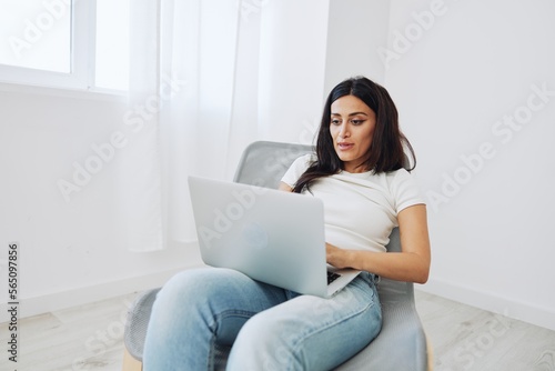 Woman relaxing at home sitting in a chair with her laptop and talking on video call with friends in covid-19, lifestyle home spirits. Mockup, free copy space © SHOTPRIME STUDIO