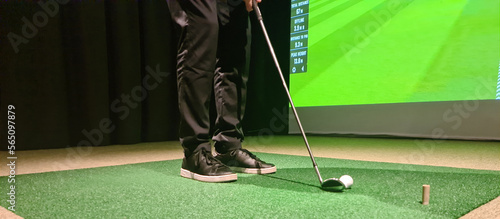 Man is playing golf on golf simulator and getting ready to hit