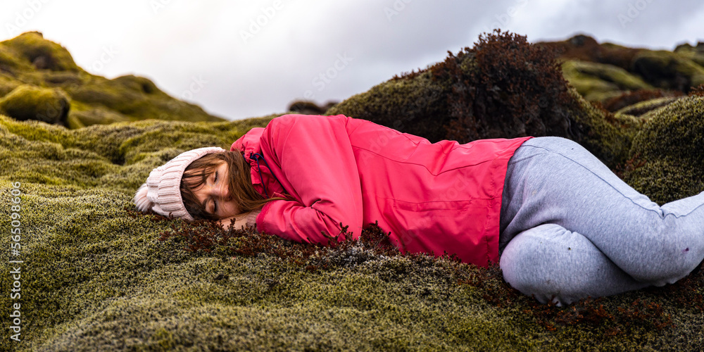 A relaxed girl lies on the soft and delicate moss covering the volcanic rocks of Iceland; the concept of coziness, comfort and softness A relaxed girl lies on the soft and delicate moss covering the volcanic rocks of Iceland; the concept of coziness, comfort and softness