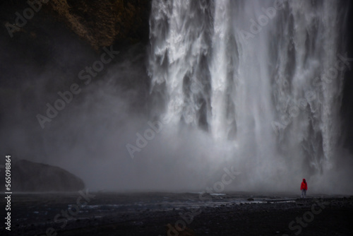 Fearless strong woman faces powerful waterfall; concept of strong and invincible woman, female strength, dangerous waterfall in iceland