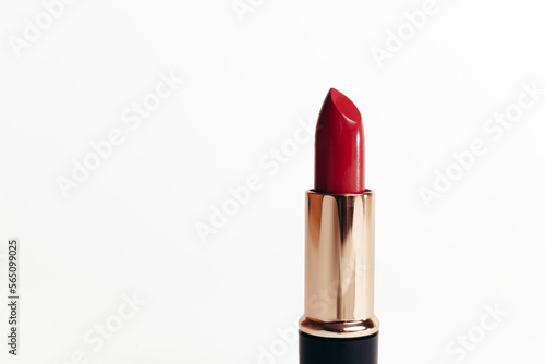 Isolated new red lipstick without cap in a golden container on a white background, macro photo