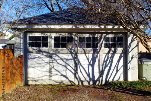 Vintage two car garage with afternoon tree shadows.