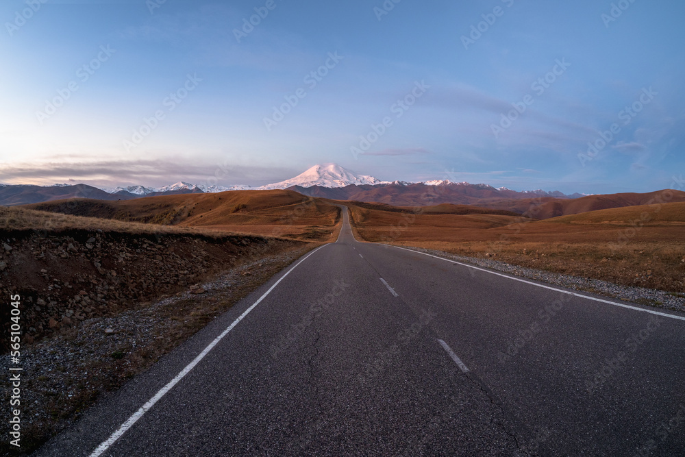 Morning highway to the snow-capped peaks. Autumn morning deserted highway. Beautiful asphalt freeway, motorway, highway through of caucasian landscape mountains hills.