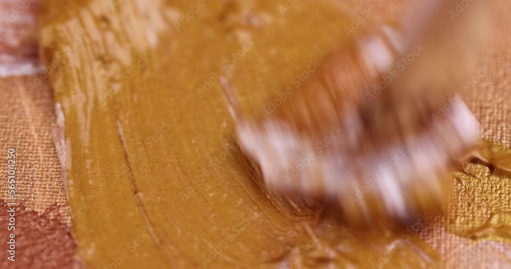 Drawing lines with a brush on a canvas with gold paints, drawing lines