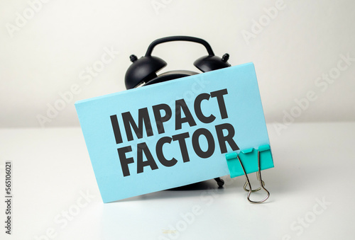 IMPACT FACTOR is written in a blue sticker near a black alarm clock