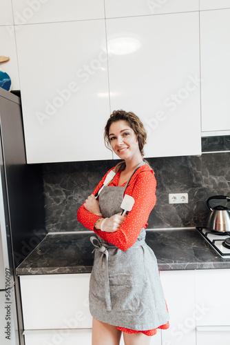 a housewife in an apron stands by a metal bowl in the kitchen