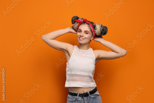 Print op canvas Beautiful woman with braided double buns on orange background, space for text