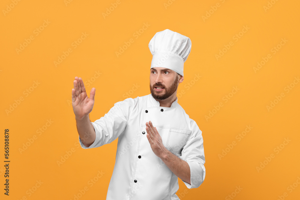 Emotional mature male chef on orange background Emotional mature male chef on orange background
