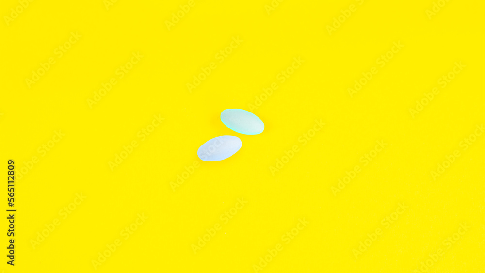 Two Pills of blue color on a yellow background. Medicine, treatment, pharmacology, health ,concept. Top view Space for text