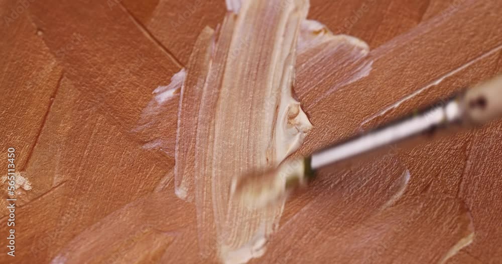 Drawing lines with a brush on a canvas with gold paints, drawing lines