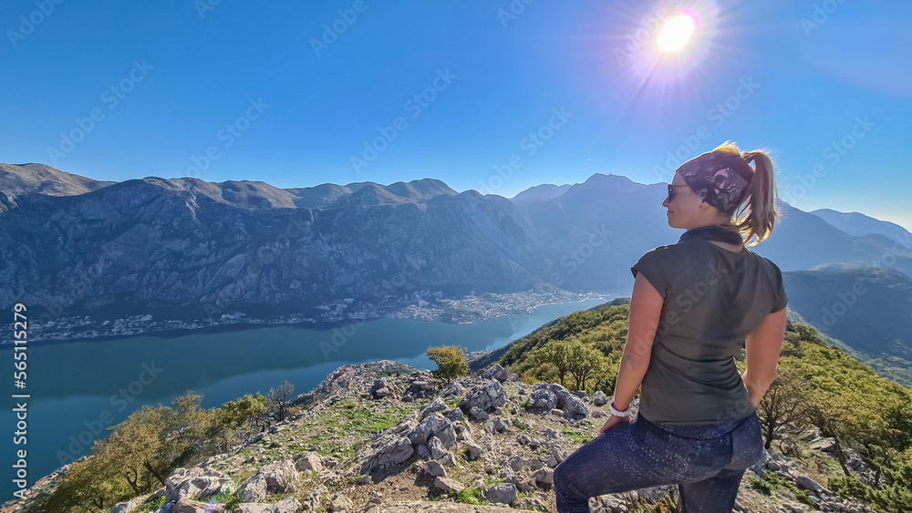 Naklejka premium Woman with scenic view from mountain summit of Vrmac Sveti Ilija on Kotor bay in summer, Adriatic Mediterranean Sea, Montenegro, Balkans, Europe. Fjord winding along coastal towns. Hiking Dinaric Alps