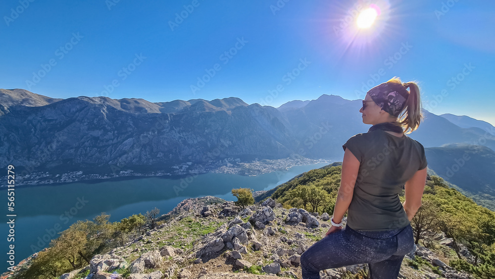 Woman with scenic view from mountain summit of Vrmac Sveti Ilija on Kotor bay in summer, Adriatic Mediterranean Sea, Montenegro, Balkans, Europe. Fjord winding along coastal towns. Hiking Dinaric Alps