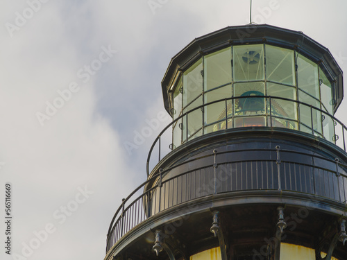 Large lighthouse tower. Close-up. The blue sky is covered with white fluffy clouds. Navigation, maritime safety, beautiful majestic building, history, culture, romance.