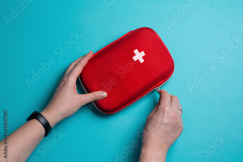 A woman opens a first aid kit. Home first aid kit on a blue background.