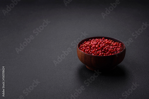 Spice, allspice peas of red or pink color in a wooden bowl