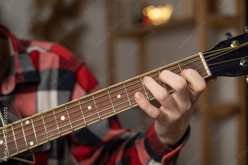 Obraz premium Guitarist plays the guitar at home. Focus on hands.